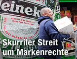 Arbeiter trägt eine Kiste vor einem Heineken-Logo