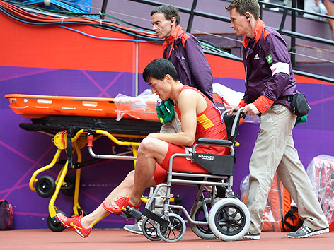 Olympia-Helfer schieben Liu Xiang im Rollstuhl