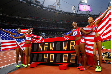US-Damenstaffel über 4x100m (Allyson Felix, Carmelita Jeter, Bianca Knight, and Tianna Madison) posiert vor einer Anzeigentafel, die die Weltrekordzeit zeigt